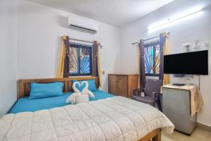 a bedroom with a bed and a flat screen tv at Baga Beach Rosy Inn in Baga
