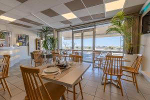 ein Esszimmer mit Tischen, Stühlen und Fenstern in der Unterkunft Logis Hôtel Rêve de Sable in Royan