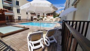 een patio met 2 stoelen, een parasol en een zwembad bij La terrasse de l'Imbut - Climatisation & Piscine in Gréoux-les-Bains