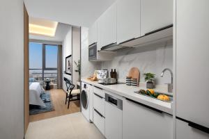 a white kitchen with a sink and a dishwasher at Ascott M-City Foshan in Foshan