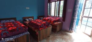 Habitación con 2 camas y 2 ventanas. en KedarDham Guest House, en Gupta Kāshi