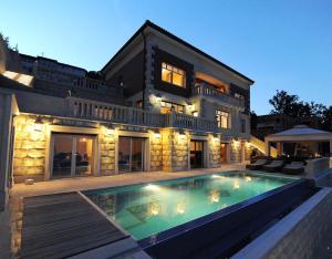a large house with a swimming pool in front of it at Apartments Villa Isabella in Opatija