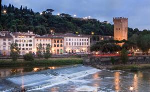 una città di notte con un fiume e edifici di LHP Hotel River & SPA a Firenze