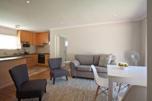 a living room with a couch and chairs and a kitchen at Sunbird Cottage in Somerset West