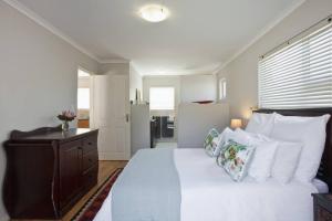 a bedroom with a large white bed with white pillows at Sunbird Cottage in Somerset West