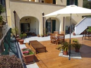 Un patio con mesas y sillas y una sombrilla. en Casa Papaveri Rossi, en Finale Ligure