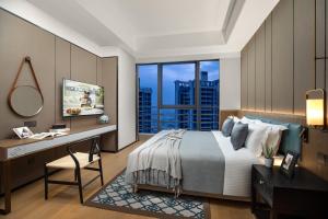 a bedroom with a bed and a desk and a window at Ascott M-City Foshan in Foshan