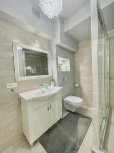 a bathroom with a sink and a toilet and a chandelier at Bonjour Apartment in Predeal +25 photos