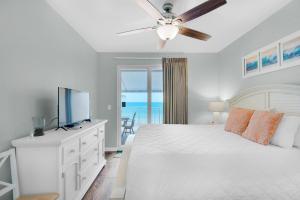 a bedroom with a bed with a ceiling fan and a television at Sterling Reef 102 in Panama City Beach