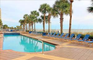 a swimming pool with blue chairs and palm trees at Sterling Reef 102 in Panama City Beach