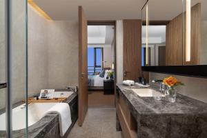 a bathroom with a tub and a sink and a bed at Ascott M-City Foshan in Foshan