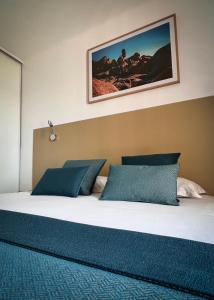 a bedroom with a large bed with blue pillows at Hotel l'Isolella in Porticcio