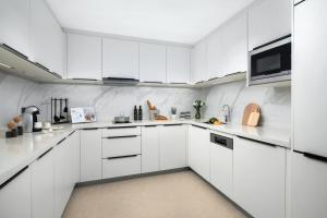 a white kitchen with white cabinets and a microwave at Ascott M-City Foshan in Foshan