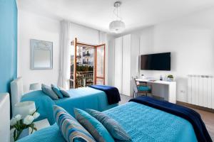a hotel room with two blue beds and a desk at Estate4home - Casa Rosangela in Sorrento