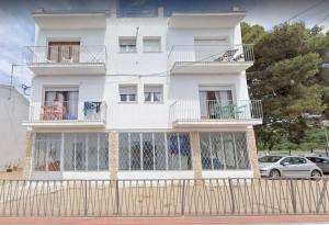 a white house with a fence in front of it at Apartamentos Juan Jose in Lloret de Mar