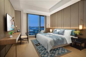 a hotel room with a bed and a desk and a window at Ascott M-City Foshan in Foshan