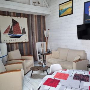 a living room with a couch and chairs and a tv at Maison typique vendéenne in La Tranche-sur-Mer