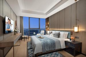 a hotel room with a large bed and a desk at Ascott M-City Foshan in Foshan