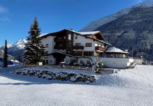 um grande edifício na neve em frente a uma montanha em Gast- und Ferienhof Christler em Tux