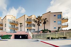 Un gran edificio de apartamentos con palmeras en un estacionamiento. en Imperial Beach Club Unit 303 Oceanfront condo, direct beach access, pool, hot tub, & private balcony, en Imperial Beach