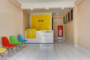 een wachtkamer met kleurrijke stoelen en een gele muur bij Super OYO 91045 Tower Mahakam By Toha Room in Bekasi
