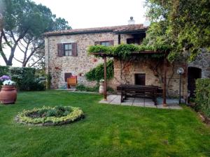 a garden with a bench in front of a stone house at Agriturismo “Sterrati” in Valpiana