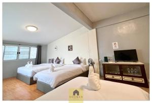 a hotel room with two beds and a television at Hooman Hostel in Chiang Mai