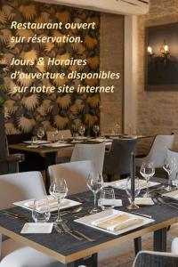 uma sala de jantar com mesas e cadeiras com copos de vinho em Ferme de la Rançonnière - Hôtel & Restaurant em Crépon