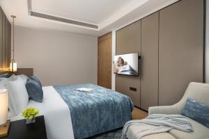 a hotel room with a bed and a tv on a wall at Ascott M-City Foshan in Foshan
