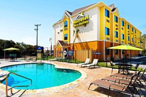 um hotel com piscina e cadeiras e um edifício em Microtel Inn & Suites by Wyndham New Braunfels I-35 em New Braunfels