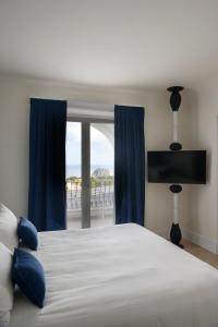 a bedroom with a bed with blue curtains and a window at La Residenza Capri in Capri