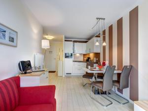 - un salon et une cuisine avec un canapé rouge et une table dans l'établissement Residenz am Balmer See - BS 04 mit Wellnessbereich, à Balm
