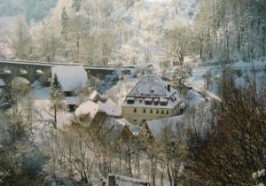 a house covered in snow next to a bridge at HERRNMÜHLE - Pension & Ferienwohnungen in Rothenburg ob der Tauber