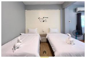two beds in a room with white sheets at Hooman Hostel in Chiang Mai