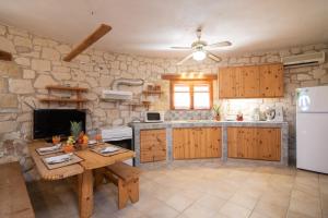 a kitchen with wooden cabinets and a table and a refrigerator at Gerakomylos Stone House in Vasilikos