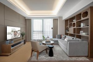 a living room with a couch and a tv at Ascott M-City Foshan in Foshan