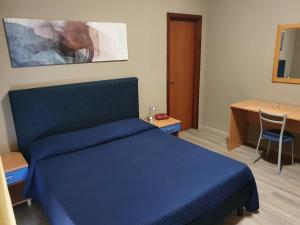 a bedroom with a blue bed and a desk at Dependance La Mouette in Termini Imerese