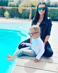 a woman and a child sitting next to a pool at Hotel l'Isolella in Porticcio