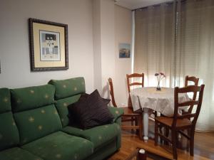 ein Wohnzimmer mit einem grünen Sofa und einem Tisch in der Unterkunft Precioso apartamento en Santander cerca de todo in Santander