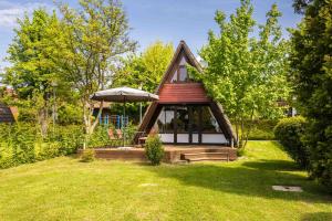 a small house with a porch and an umbrella at Ferienwohnpark Immenstaad am Bodensee Nurdachhaus Typ 7 ND 45 in Immenstaad am Bodensee