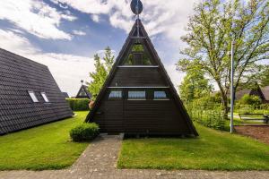 a house with a triangular roof on the grass at Ferienwohnpark Immenstaad am Bodensee Nurdachhaus Typ 7 ND 45 in Immenstaad am Bodensee