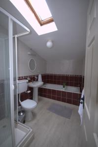 a bathroom with a toilet and a tub and a sink at Lizzys Little Kitchen Town Accommodation in Listowel
