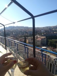 una persona che tiene un bicchiere di vino sul balcone di Di Palma Suite Museum a Napoli