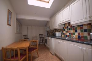 a kitchen with white cabinets and a table and chairs at Lizzys Little Kitchen Town Accommodation in Listowel