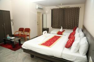 a hotel room with a large white bed with red pillows at Soundarya Hotel in Bangalore