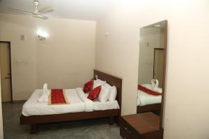 a bedroom with two beds and a mirror at Soundarya Hotel in Bangalore