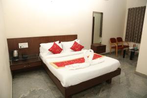 a hotel room with a large bed with red pillows at Soundarya Hotel in Bangalore