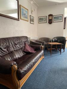 a living room with a leather couch and a table at Whiteways Guest House in Skegness