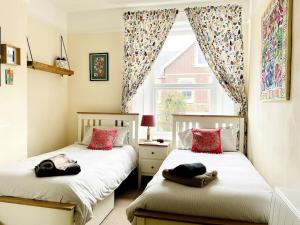 2 camas en una habitación pequeña con ventana en Unique 2-bedroom Coastal Town Retreat en Kingsbridge