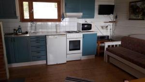 a small kitchen with blue cabinets and white appliances at Mellangårds stugor - Stockstugan in Föglö +5 photos